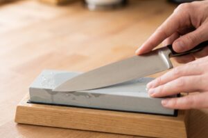 Manos afilando un cuchillo de cocina sobre una piedra de afilar
